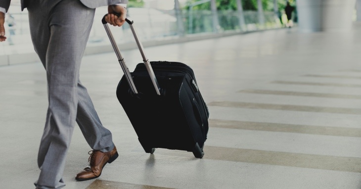Čovek u poslovnom odelu vuče svoj kofer