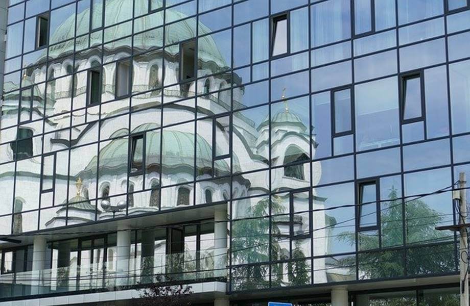 Fotografija hrama Svetog Save u Beogradu koji se ogleda u staklenoj zgradi