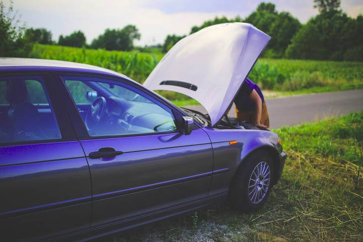 Prikaz zaustavljenog automobila i čoveka koji ga popravlja