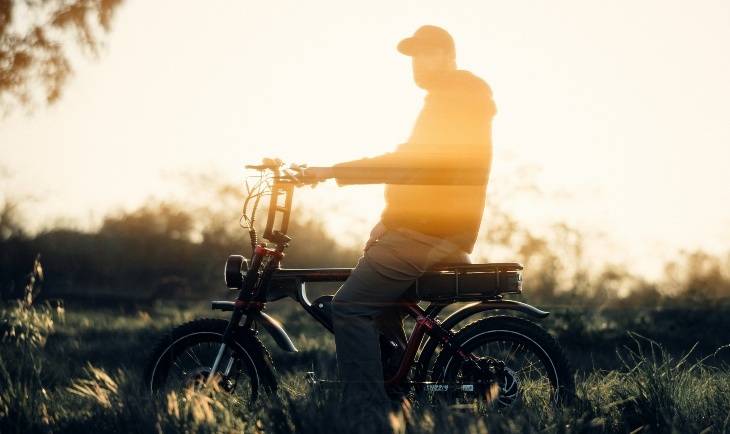 Čovek na bicikli, sunce u pozadini.