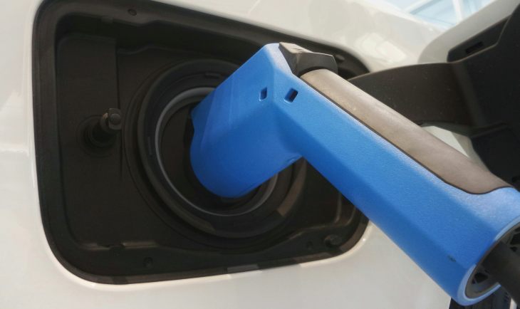 Plavo-crni električni punjač za automobile priključen na beli auto