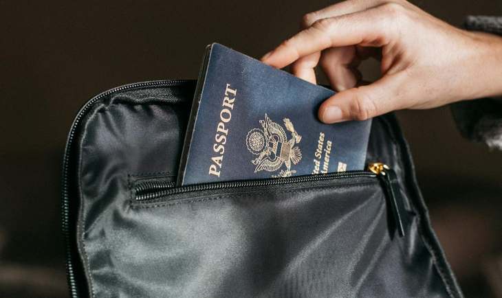 Osoba stavlja pasoš u torbu.