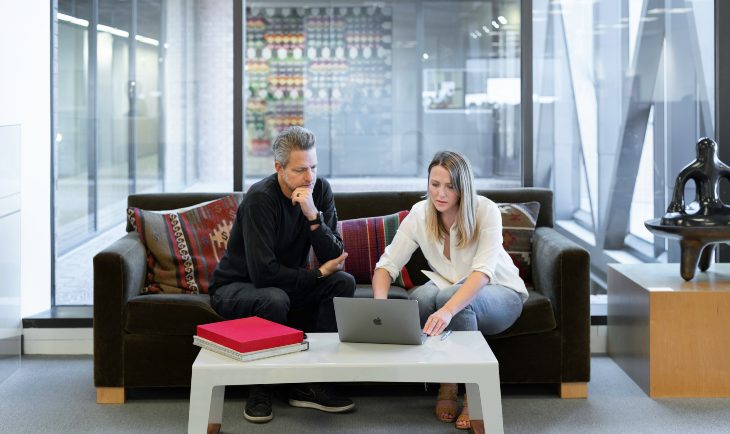 Muškarac i žena sede na kauču i gledaju u laptop