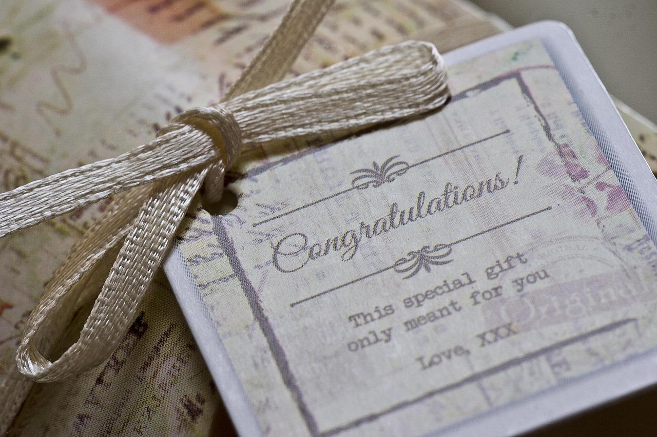 Poklon etiketa sa natpisom Congratulations i zlatnim čvorom.